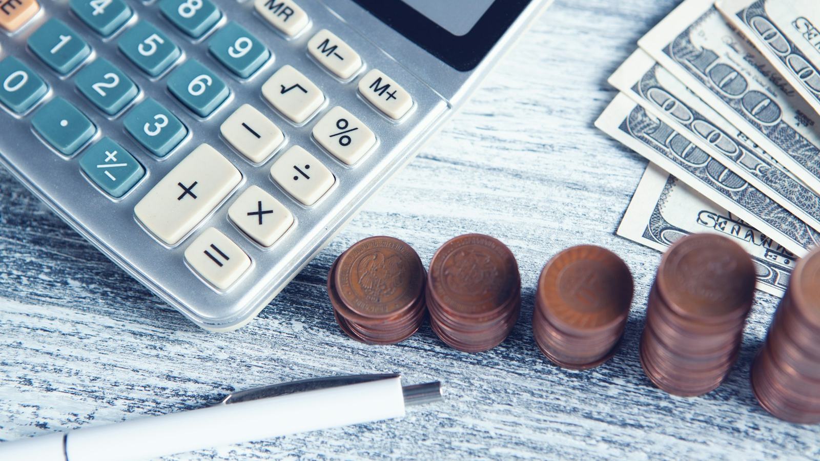 Calculator beside stacked coins and dollar bills