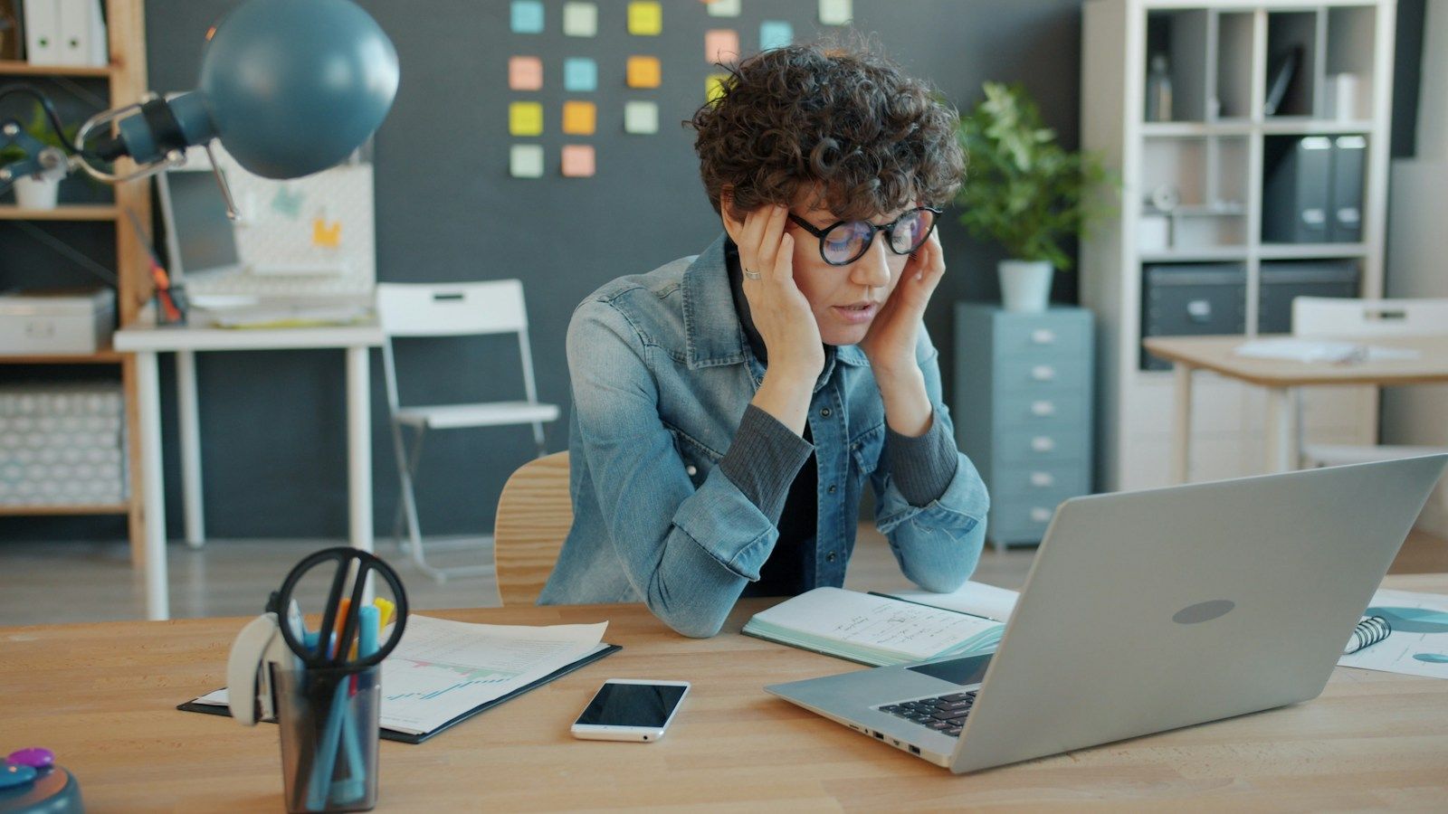 Stressed person holding their head while working at a laptop